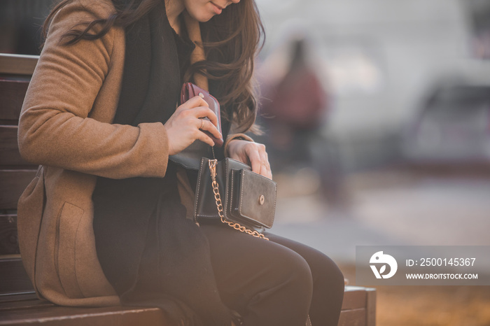 woman looking different stuff in her purse sitting on city bench