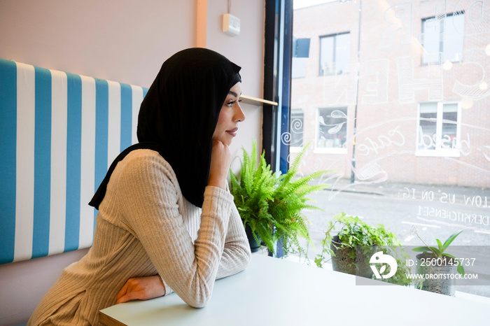 Young woman in hijab sitting in cafe