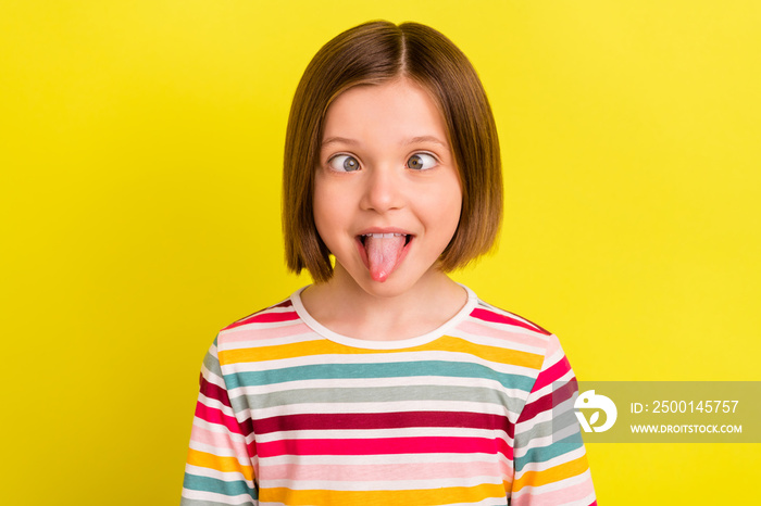 Photo portrait little girl with bob hairstyle fooling showing tongue grimacing isolated vibrant yellow color background