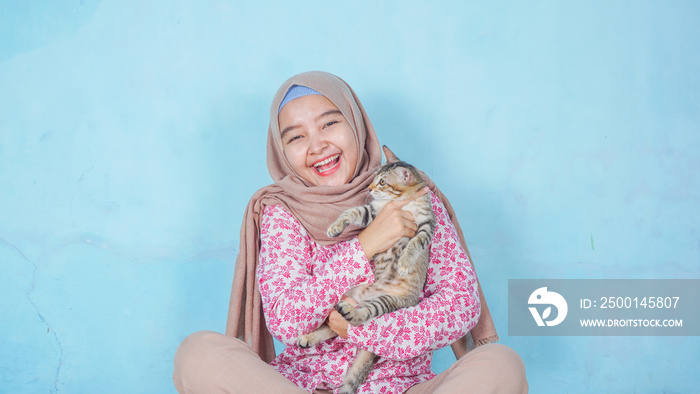 portrait of the asian hijab woman with cat on the color background - free copy space for text