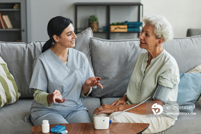 Portrait of smiling senior woman talking to female nurse in retirement home, copy space