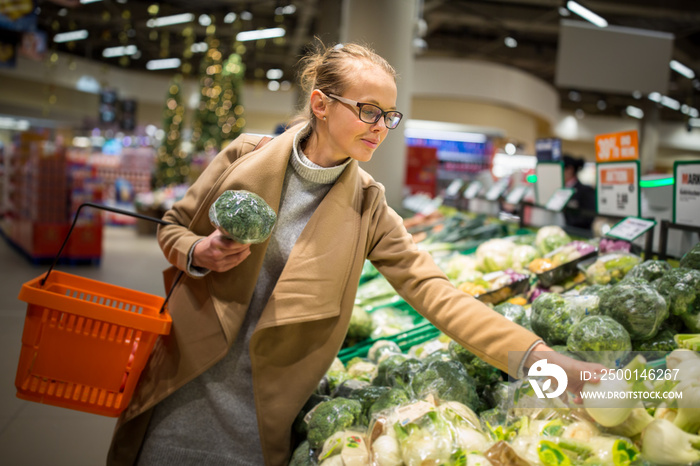 shopping, food, sale, consumerism and people concept - happy woman at grocery store or supermarket buying vegetables