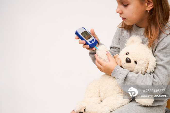 Little girl checking diabetes test to toy bear