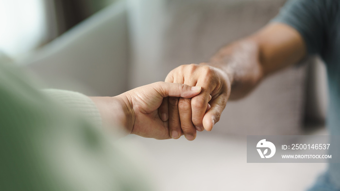 Female friend or family sitting and hold hands during cheer up to mental depress man, Psychologist provides mental aid to patient. PTSD Mental health concept.