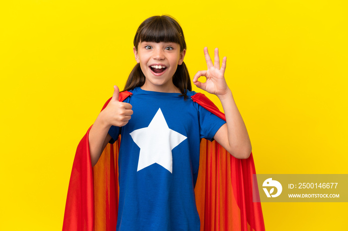 Little super hero kid isolated on purple background showing ok sign and thumb up gesture