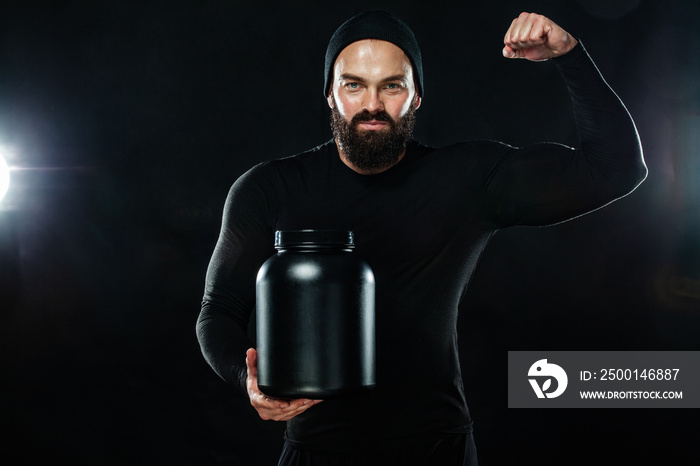 Happy and healthy muscular young fitness sports man with a jar of sports nutrition - protein, gainer and casein