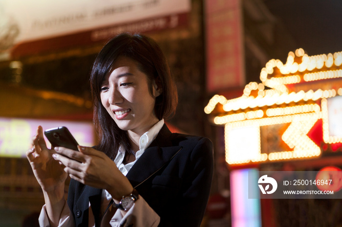 Businesswoman using cellular phone, night market, Taipei, Taiwan