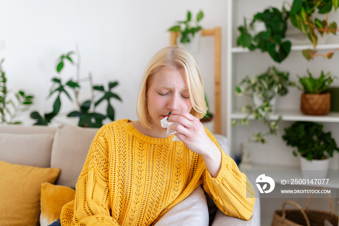 Sick Woman.Flu.Woman Caught Cold. Sneezing into Tissue. Headache. Virus .Medicines. Young Woman Infected With covid 19 Blowing Her Nose In Handkerchief. Sick woman with a headache sitting on a sofa