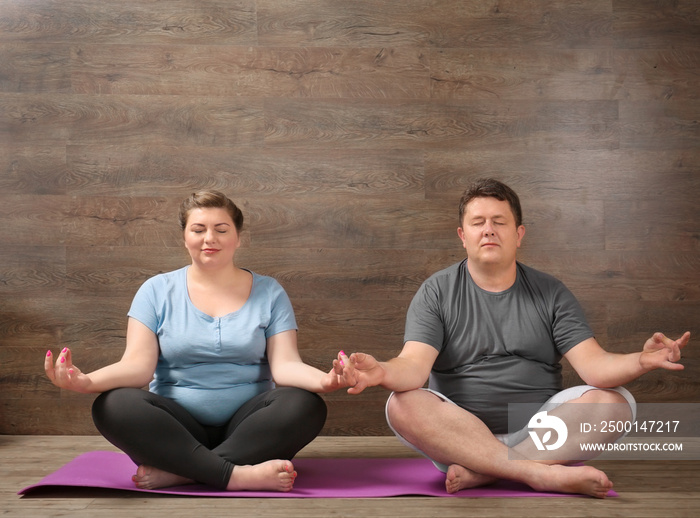 Overweight couple training together against wooden wall