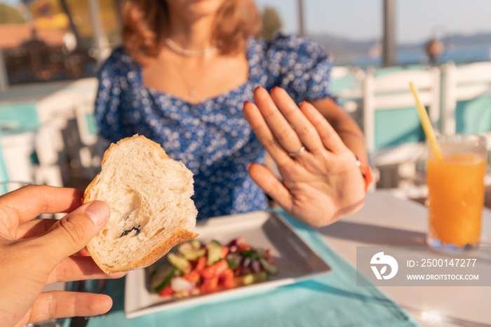 A woman refuses bread toast in a restaurant. Intolerance and allergy to gluten or a diet for weight loss