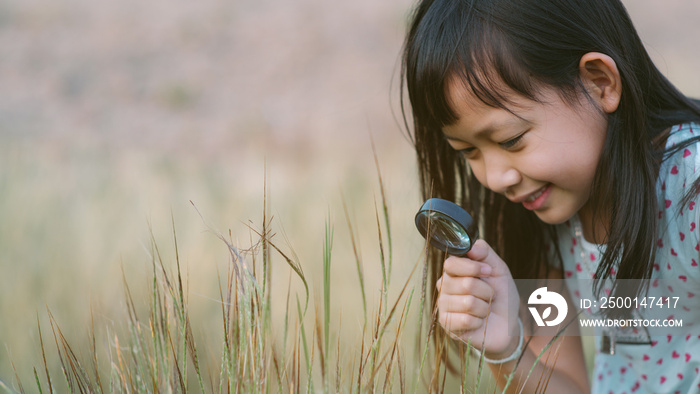 Happy asian child girl exploring nature with magnifying glass.16:9 style