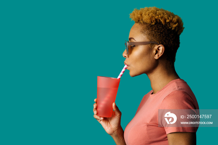 Profile portrait of a cool young  woman in pink holding a drinking cup and paper straw