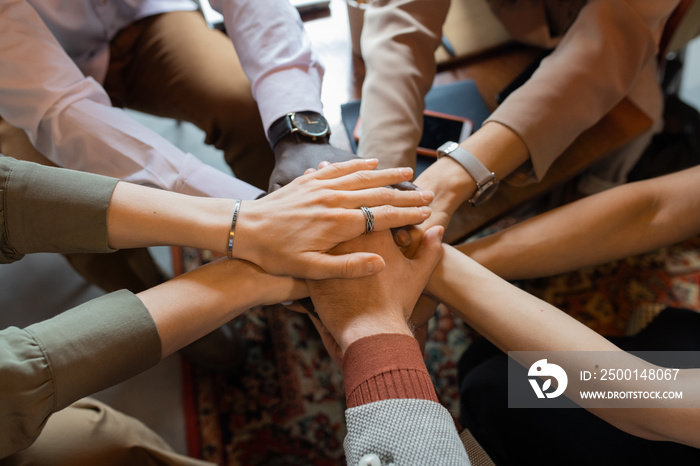 Pile of hands of several intercultural colleagues symbolizing teamwork and support