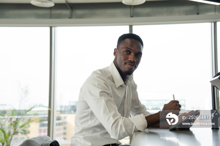 Portrait of young businessman using digital tablet in office