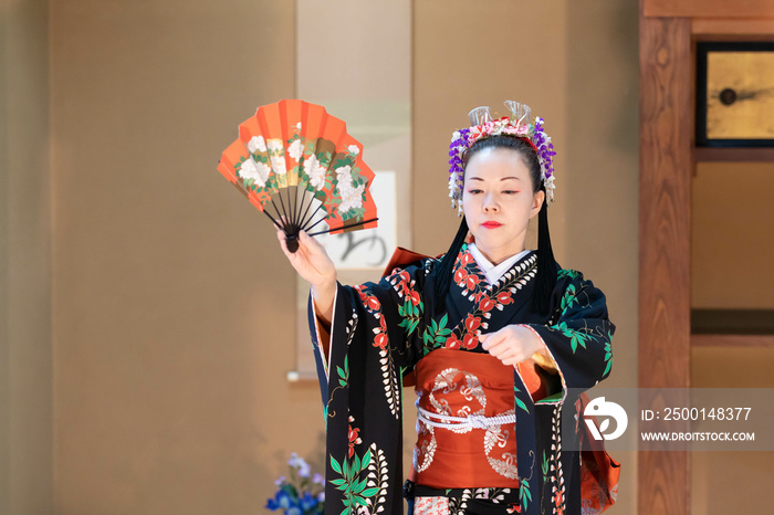 着物姿で扇子を持って日本舞踊を踊る若い日本人女性