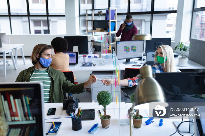 Caucasian business people wearing face masks in creative office