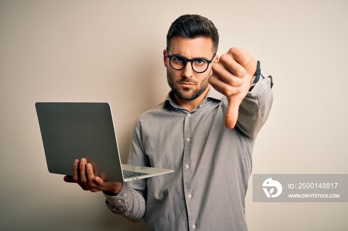 Young business man wearing glasses working using computer laptop with angry face, negative sign showing dislike with thumbs down, rejection concept