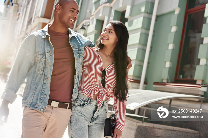 Romantic Relationship. Young diverse couple walking on the city street hugging looking at each other talking smiling happy