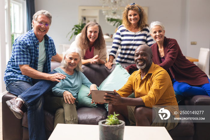 Portrait of smiling multiracial senior male and female friends on sofa at home