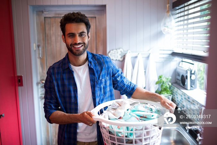 Portrait of smiling young man holding laundry basket