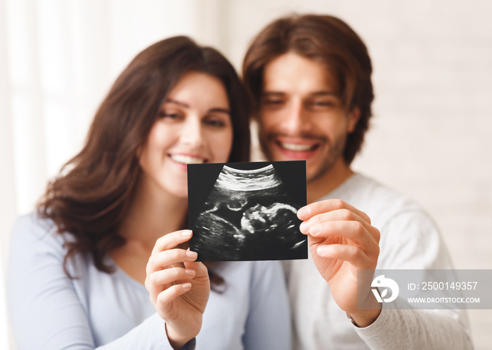 Happy young couple looking at sonography picture of their baby