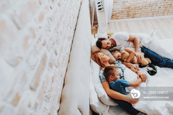 Happy beloved family sleeping together in bed