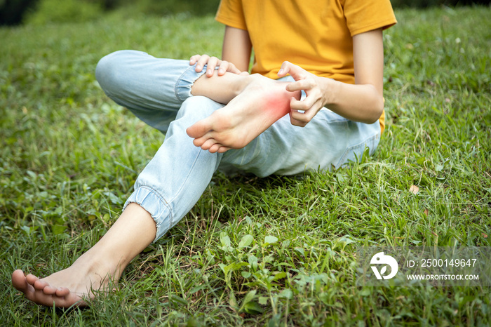 Asian child girl scratch on her foot with hand,foot itch allergy,rash in the grass at park,teenage doesn’t wear shoes or walk barefoot will get parasitic in to the skin cause feet itching,Anaphylaxis