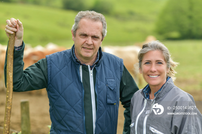 Portrait of a farmer couple standing outdoors in front of their cattle  in their cows farm