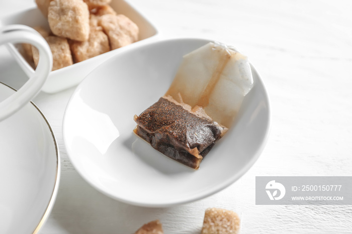 Plate with used tea bag on table