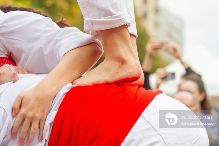 Barefoot unrecognizable person doing Castellers or Torre Humana, typical tradition in the festivities of Catalonia (Spain).