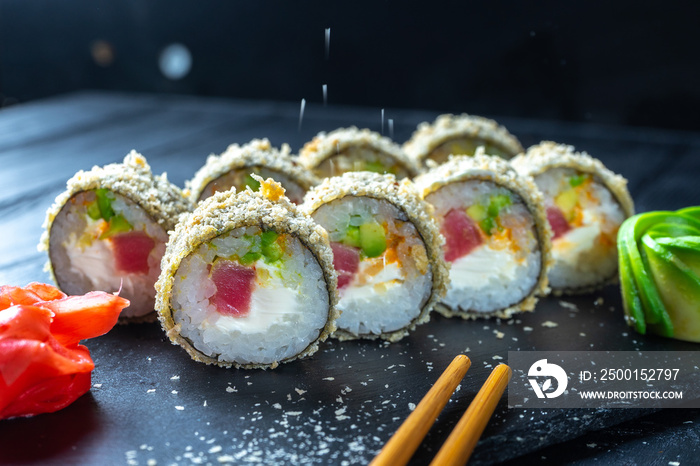 Close up fried sushi roll with cream cheese and tuna. Sushi on stone dark plate on black wooden background with copy space. Japanese food. Seafood. Dieting, healthy food. Warm sushi