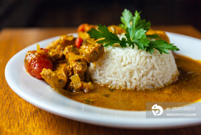 Curry chicken bright juicy with white rice on plate over wooden background. side view.