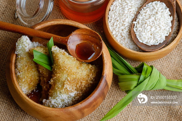 Kue lupis as traditional Indonesian sweet sticky rice dumplings of glutinous rice with grated or shredded coconut and palm sugar syrup