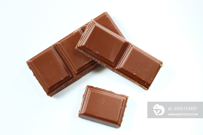 Brown chocolate in cubes on a white background close up