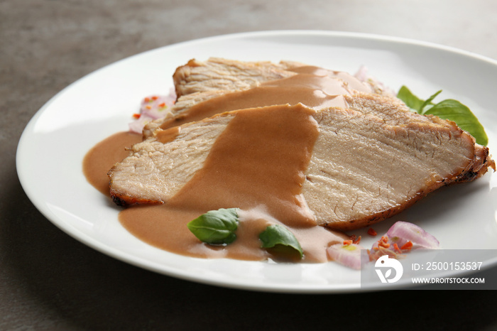 Plate with delicious sliced turkey and gravy on table