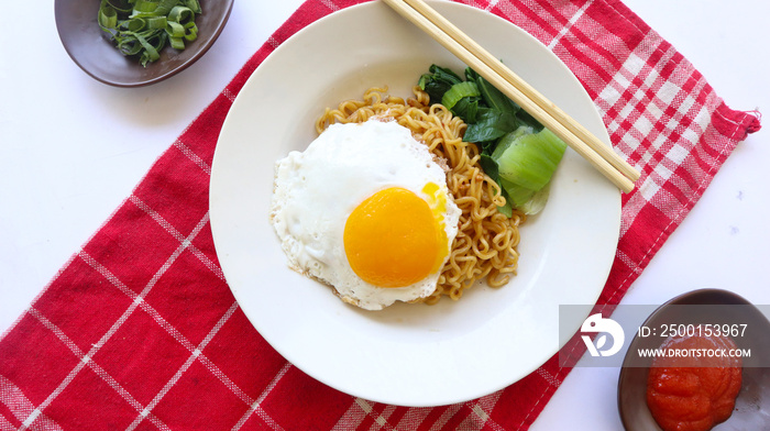 instant noodles served with egg fried and mustard greens on plate. instant fried noodle indomie