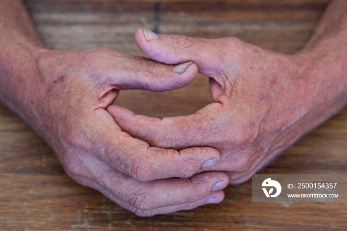 The rough hands of a working man on a table.