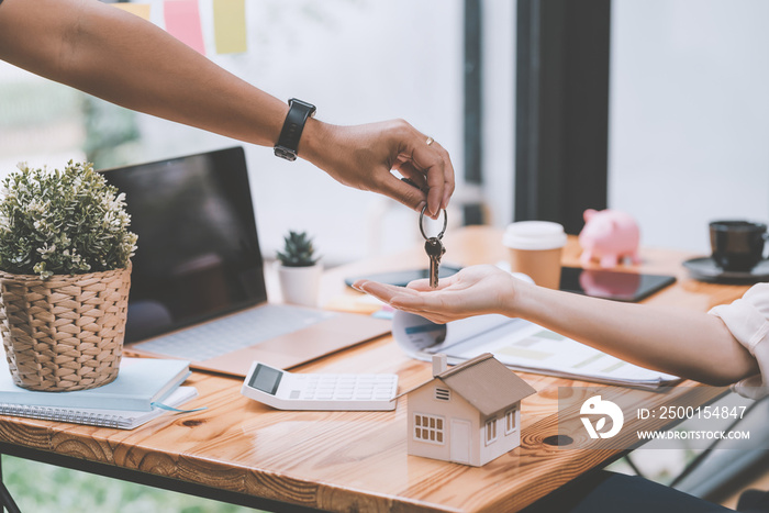 Close-up of real estate agent hands handing keys to clients at office