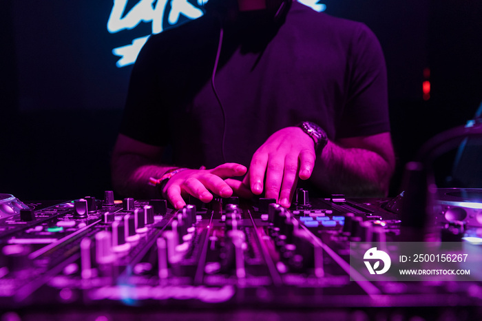 Close up view of a dj’s hands playing the mixer while performing