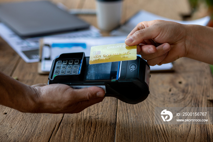 Hands of cafe visitor holding credit card and putting it to the card payment machine,modern bank payment terminal to process acquire credit card payments,