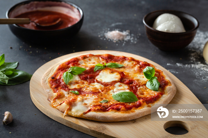 Pizza Margherita on black stone background. Classic Italian Pizza Margarita with Tomato sause, Basil and Mozzarella Cheese background.