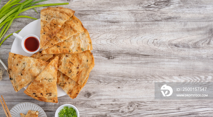 Taiwanese food - delicious flaky scallion pie pancakes on bright wooden table background, traditional snack in Taiwan, top view.