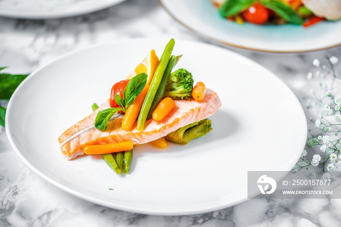 steamed salmon steak with vegetables on a white marble table