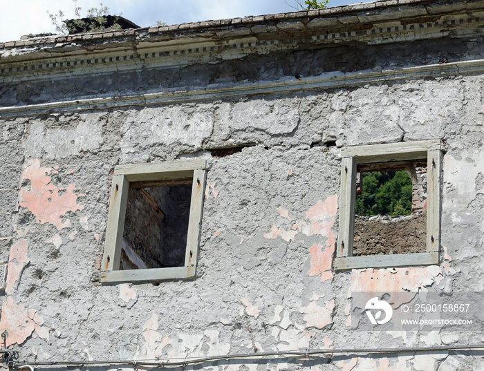 windows without the frames of a completely destroyed house without the roof and abandoned