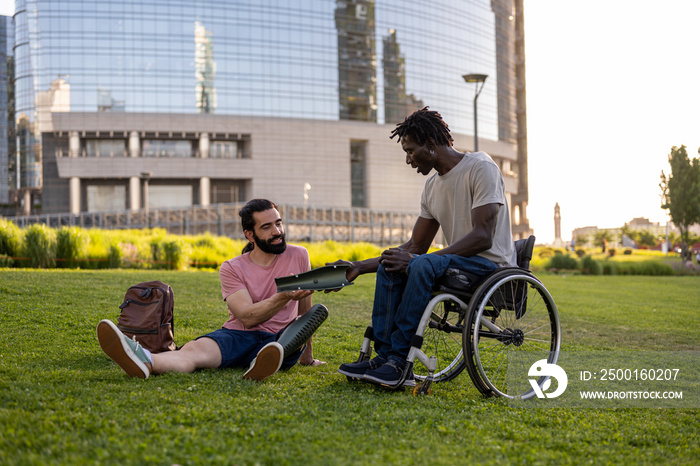 Two friends with different disabilities talking to the park about their health, moment of interaction between people with artificial leg and wheelchair use