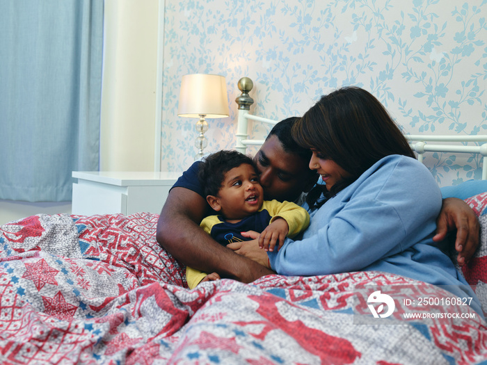 Parents hugging son in bed