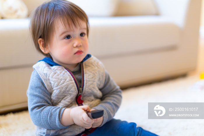 Toddler boy watching television with a remote control