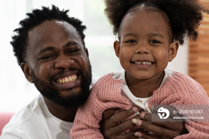 Father and daughter playing together at home. Happy African American small girl kid playing with dad