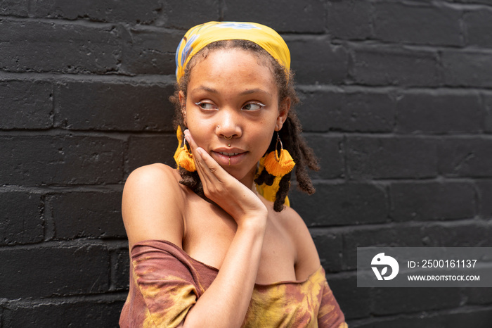 Portrait of young woman standing against brick wall