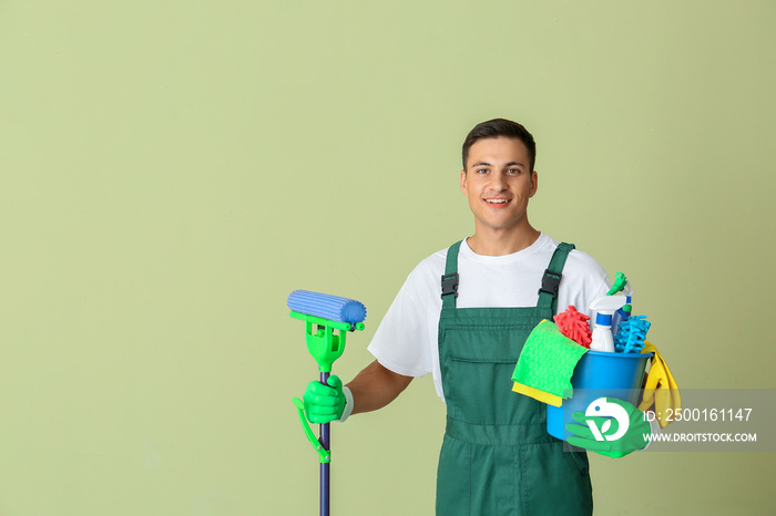 Young man with cleaning supplies on color background